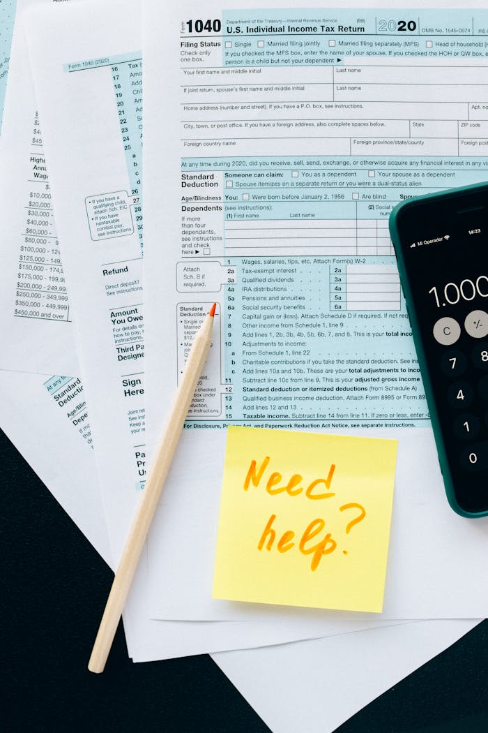 about-us Close-up of tax forms with a calculator and a note asking for assistance.